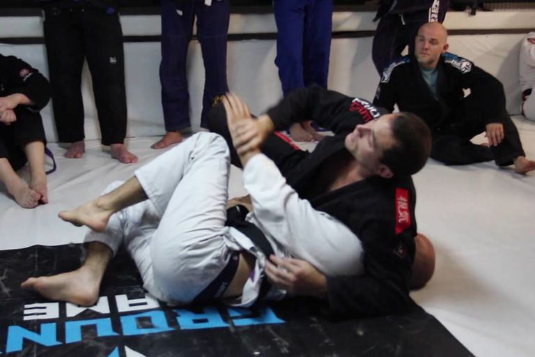 Athlete attacking an armbar from guard during live rolling